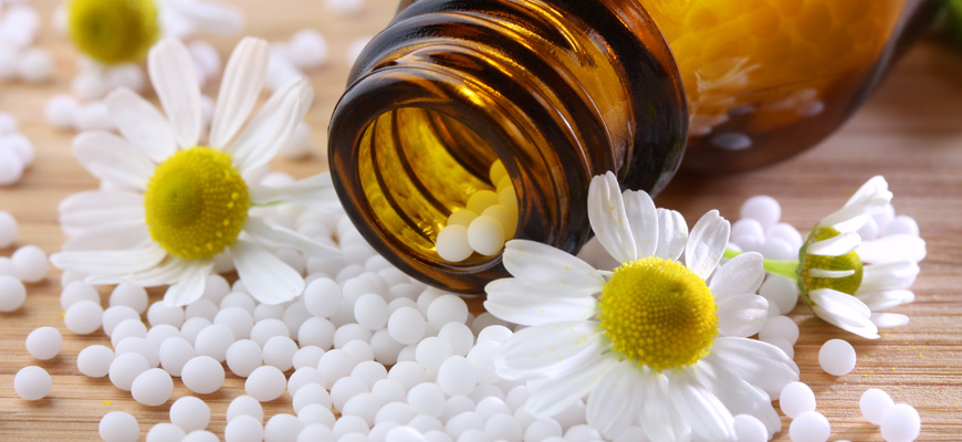 Bouteille de produits homéopathiques entourée de fleurs